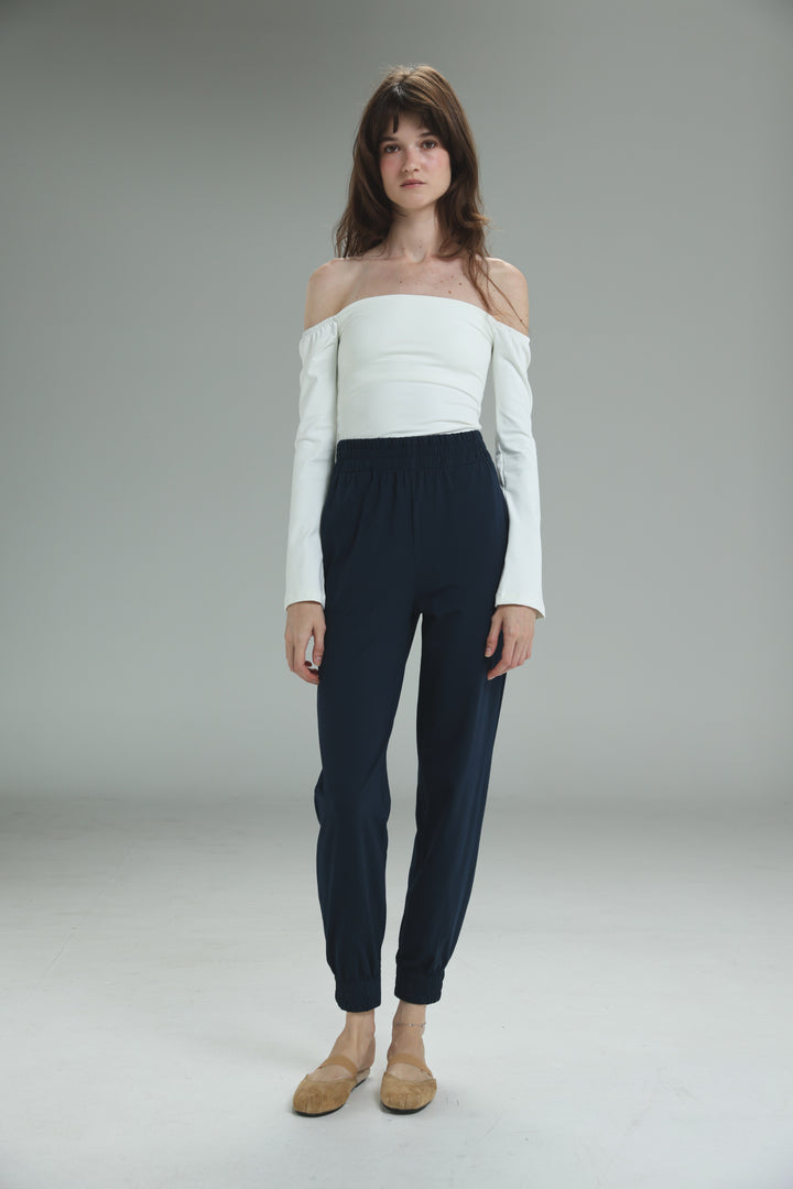 The bestie navy joggers are high-waisted with a front view paired with a white off-the-shoulder long-sleeved top