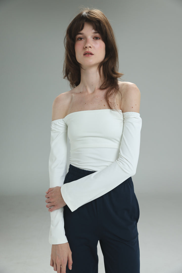 White off shoulder top with long sleeves, fitted bodice, and flared cuffs shown from the front view
