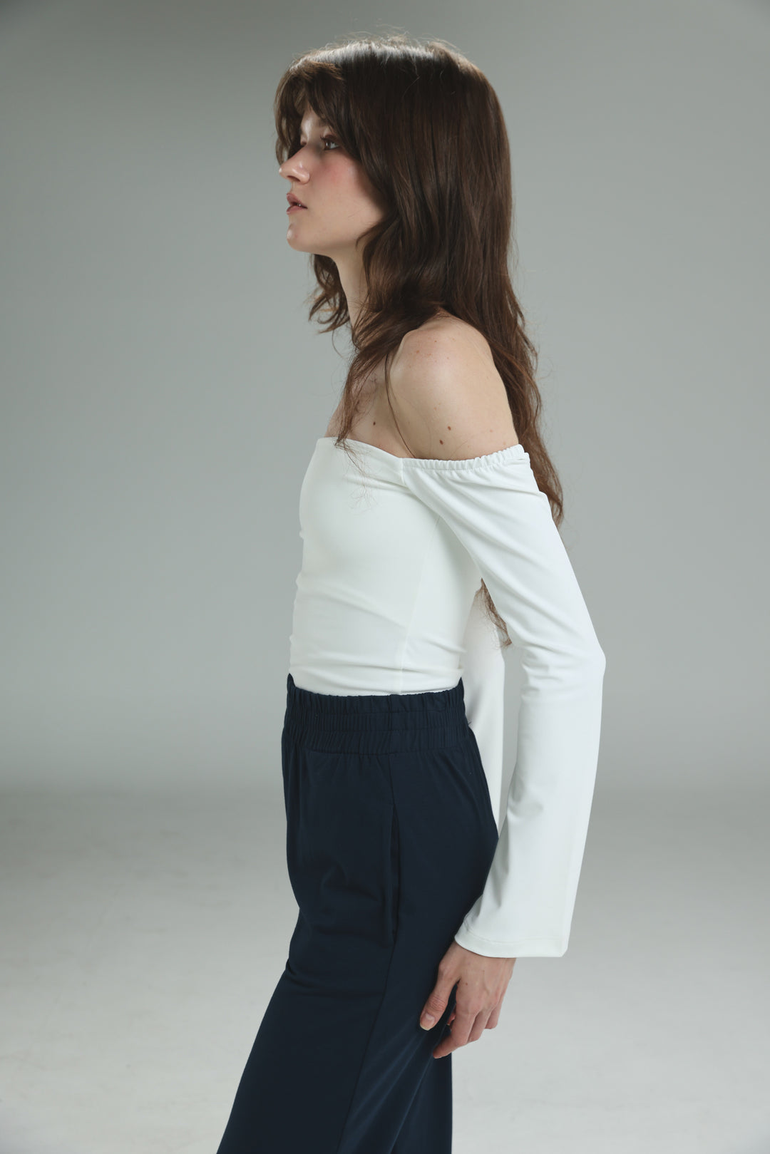 White off shoulder top with long fitted bodice and relaxed slightly flared sleeves shown from the front