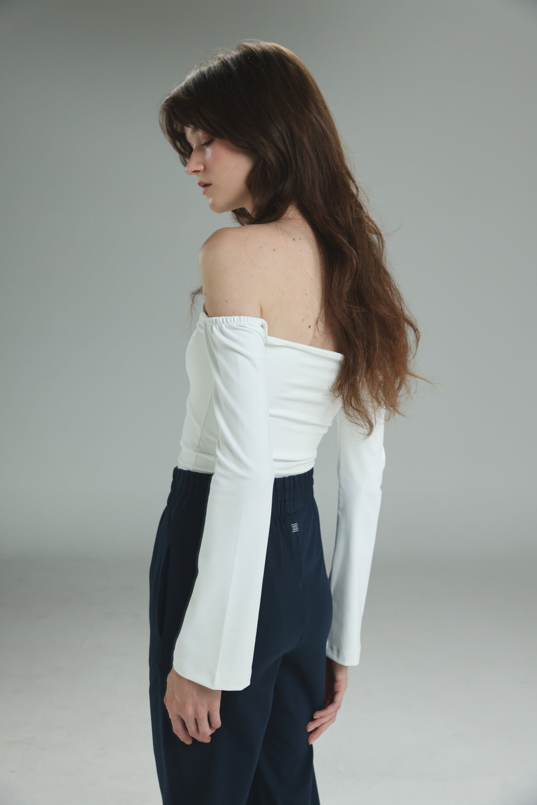 White off shoulder top with long sleeves and flared cuffs shown from the front