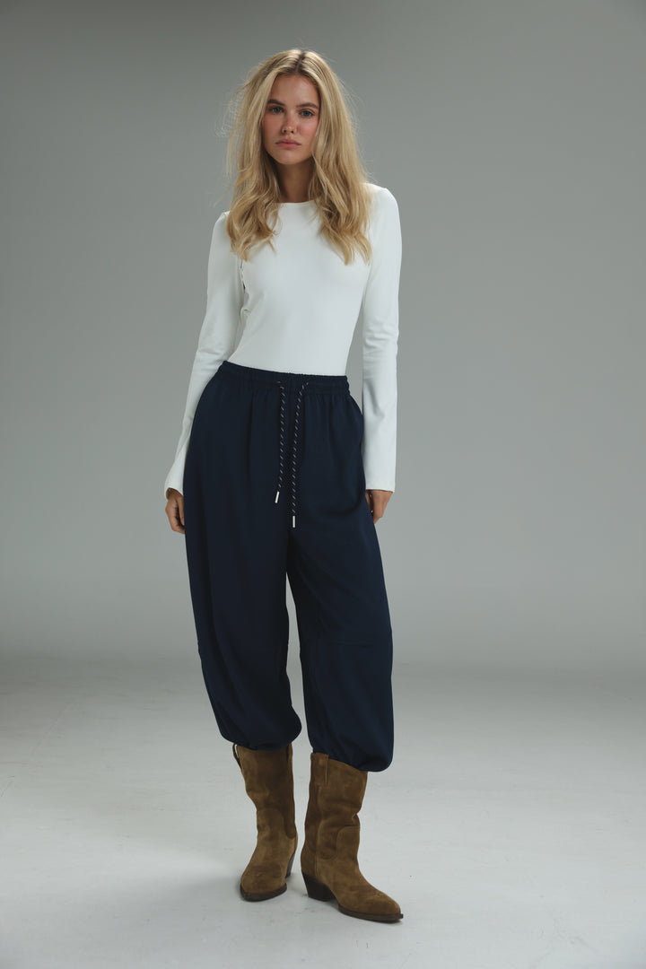 Navy blue high-waisted drawstring pants with a relaxed tapered fit and cuffed ankles shown from the front