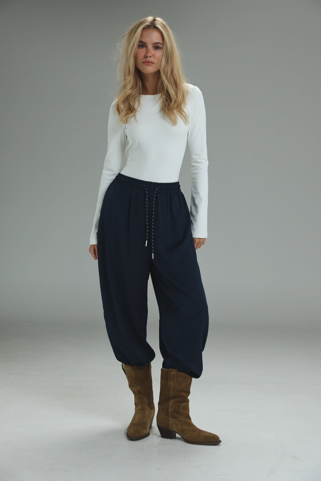 Navy blue high-waisted drawstring pants with a relaxed tapered fit and soft texture shown from the front