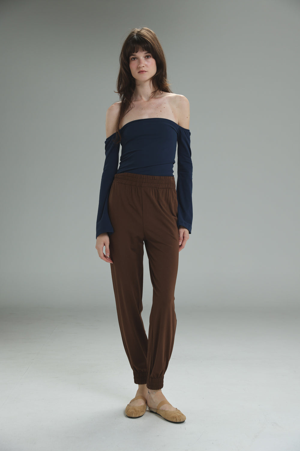 Navy blue off the shoulder long sleeved top with fitted bodice and relaxed flowing fabric front view
