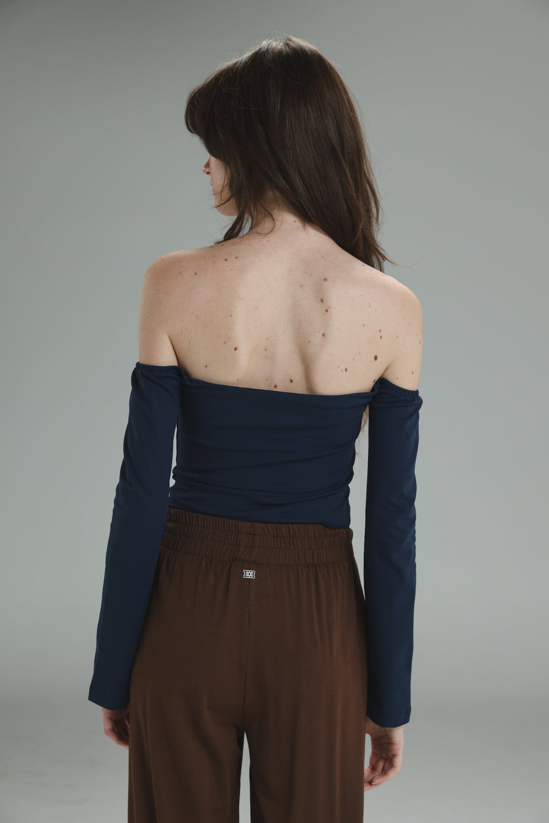 A navy lycra off shoulder top with long sleeves, fitted bodice, and gathered fabric at the shoulders viewed from the front