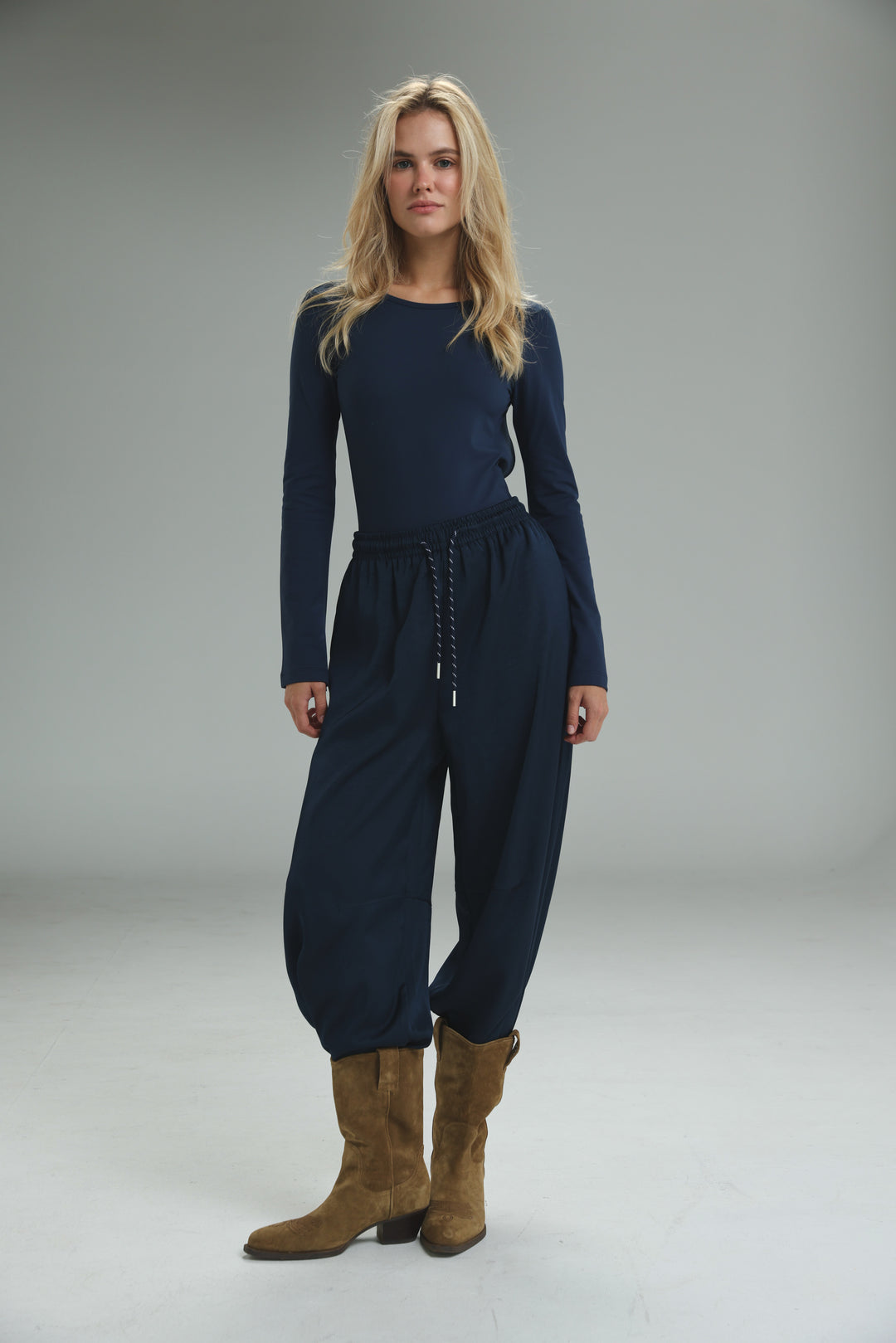 Navy blue long-sleeved jumpsuit with drawstring waist and tapered balloon-style pants shown from the front