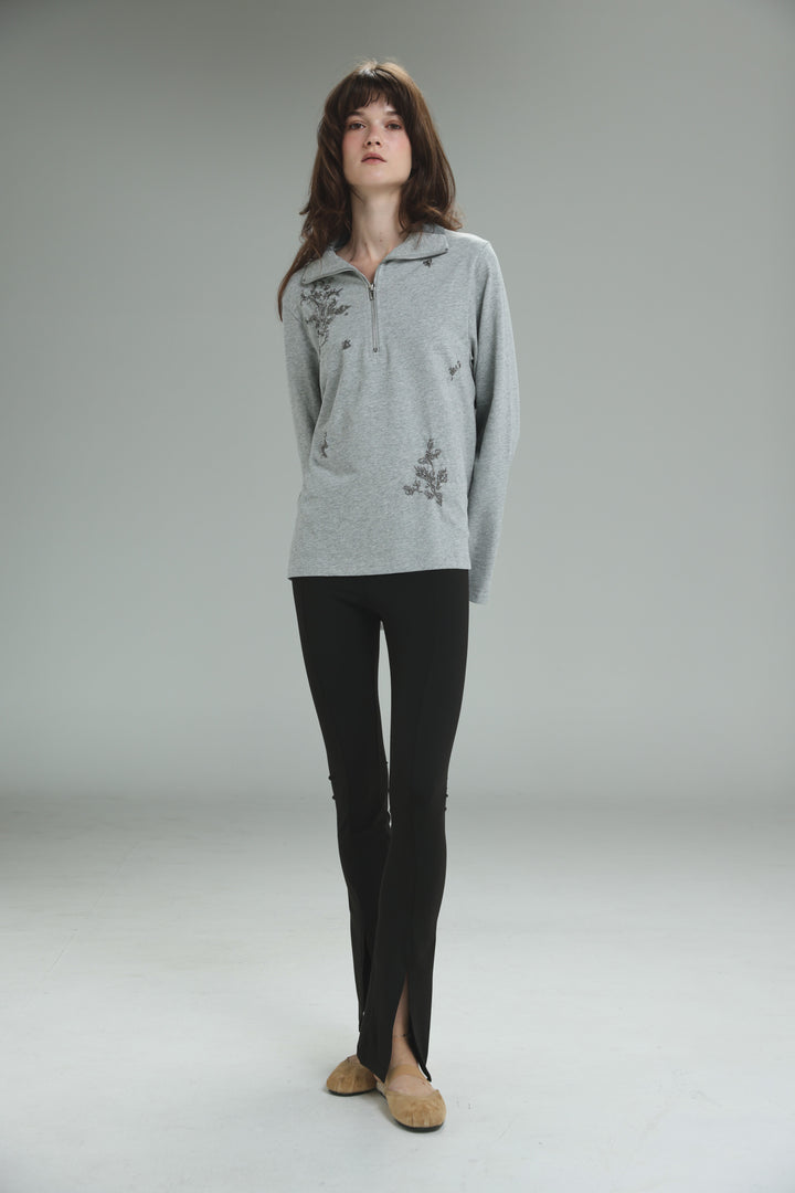 Light gray long-sleeved Joy Grey Polo with delicate floral embroidery and a half-zip neckline shown from the front