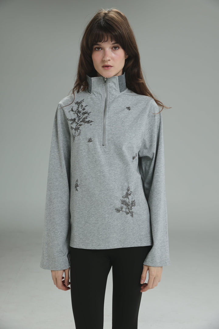 Joy grey polo long-sleeved half-zip sweater with black embroidered floral patterns shown from the front