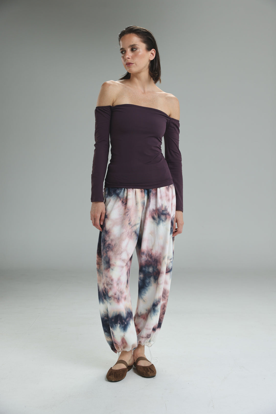 Front view of a lycra purple off shoulder top paired with loose-fitting pink white and navy blue tie-dye harem pants