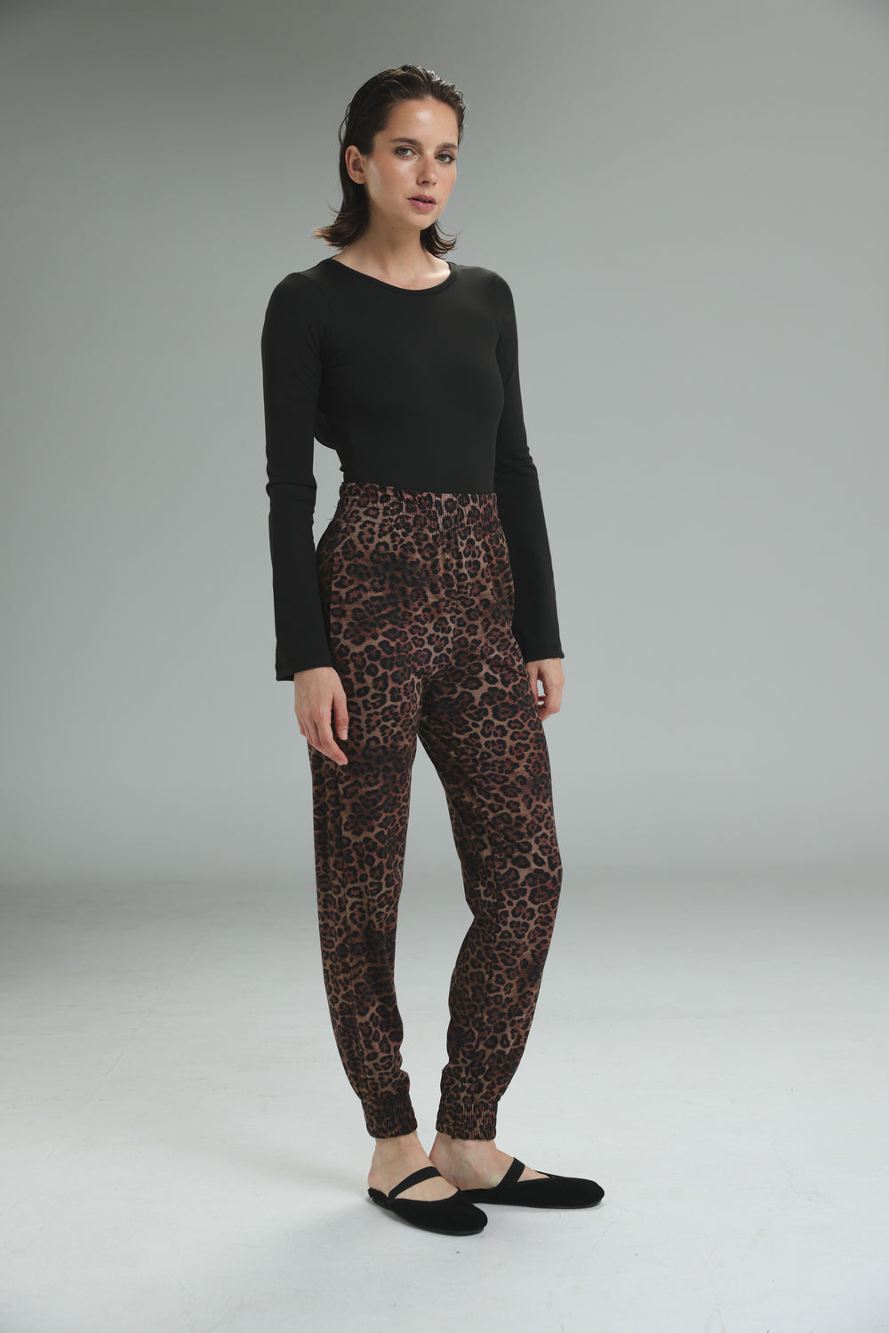 Brown leopard-print jogger pants with a snug fit and elastic cuffs shown from the front