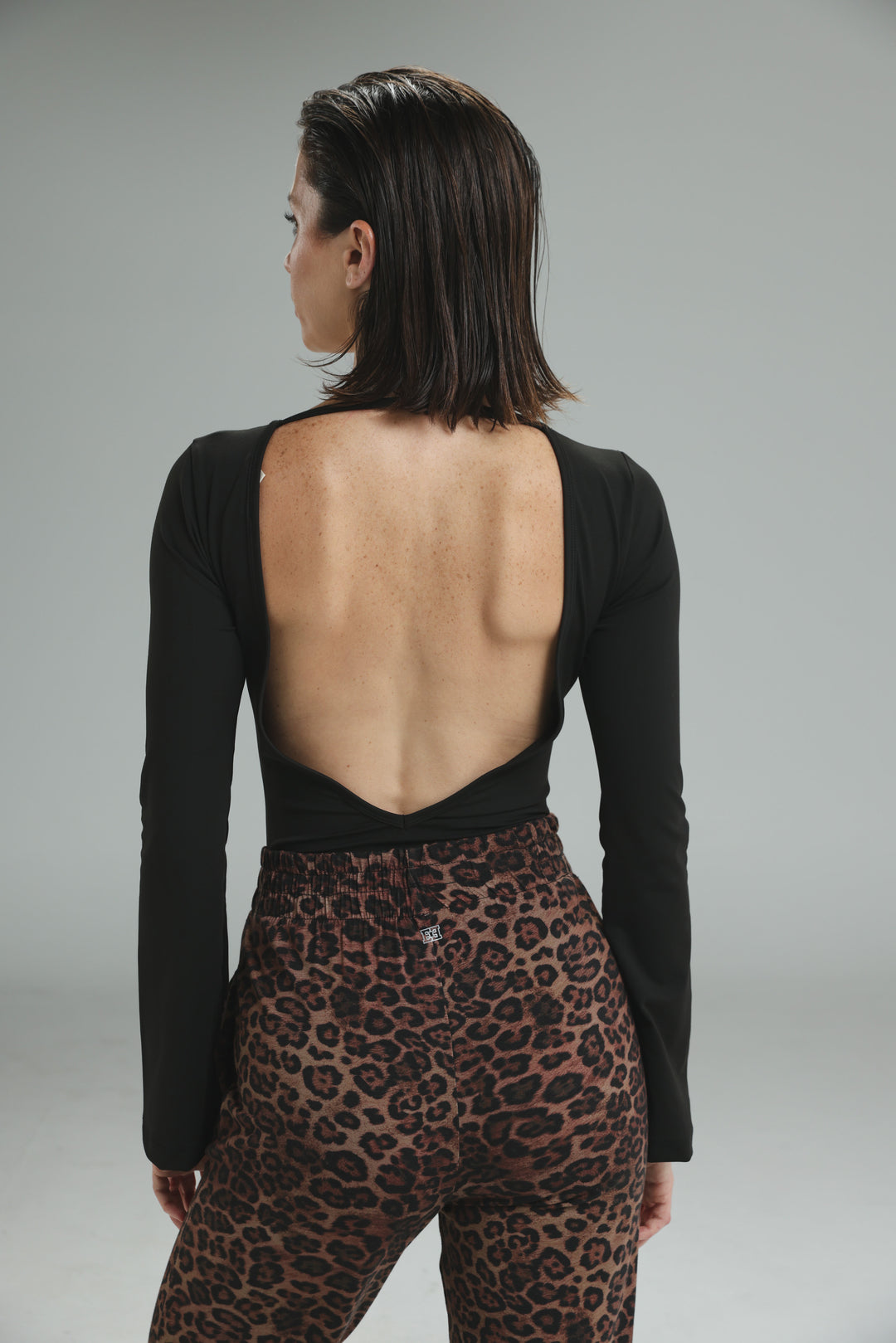 Black lycra long-sleeved bodysuit with deep open back design shown from the back view
