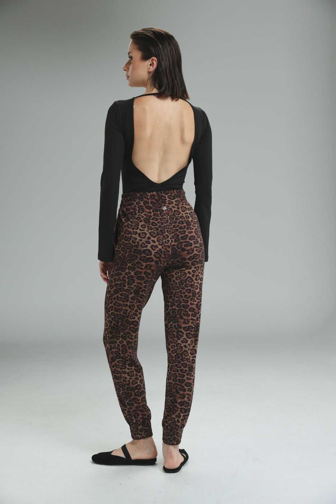 Lycra black long-sleeved open back bodysuit paired with high-waisted leopard print leggings shown from the back