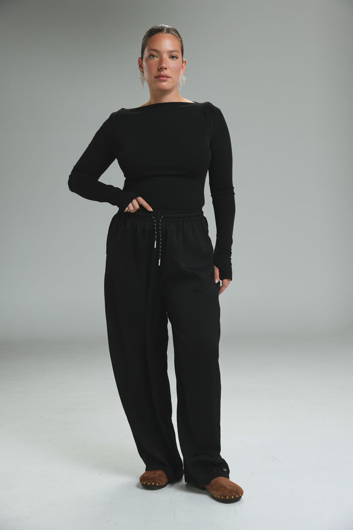 Black long-sleeved top with boat neckline and ribbed cuffs paired with golden navy bottoms shown from the front