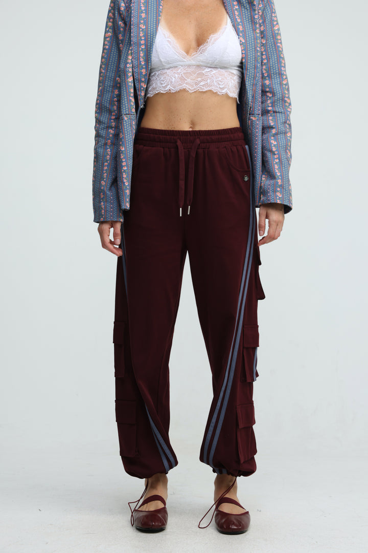 Maroon velour joggers with striped side panels and tiered cargo pockets shown from the front