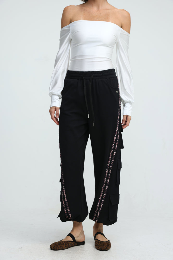 Black wide-leg jogger pants with leopard print trim along side seams and layered ruffle detailing shown from front