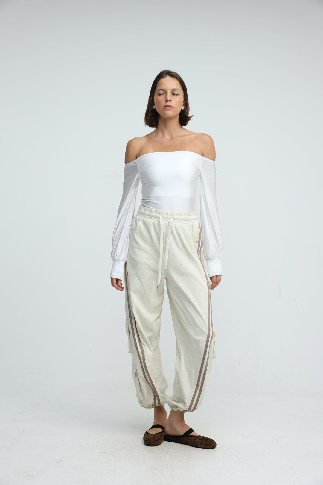 Off the shoulder white long sleeve top with relaxed fit paired with port cream joggers shown from the front