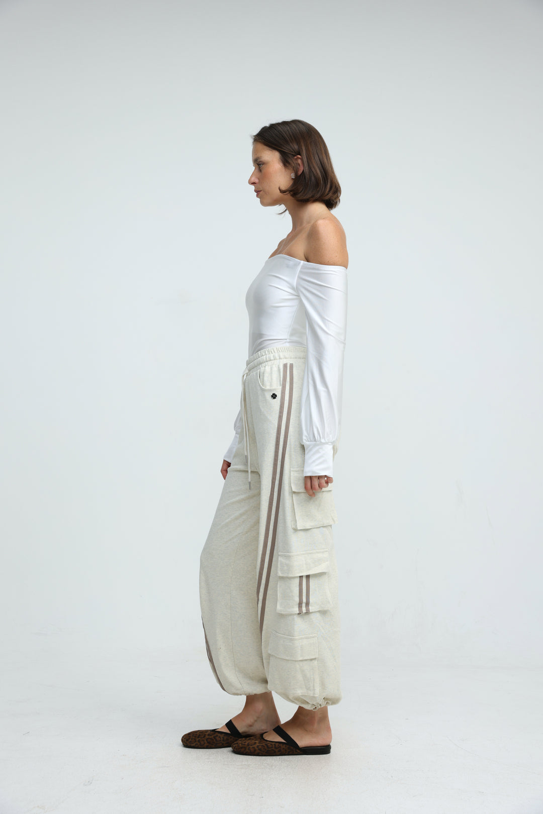 Off-white cargo joggers with beige vertical stripes and multiple front and side pockets shown from the front