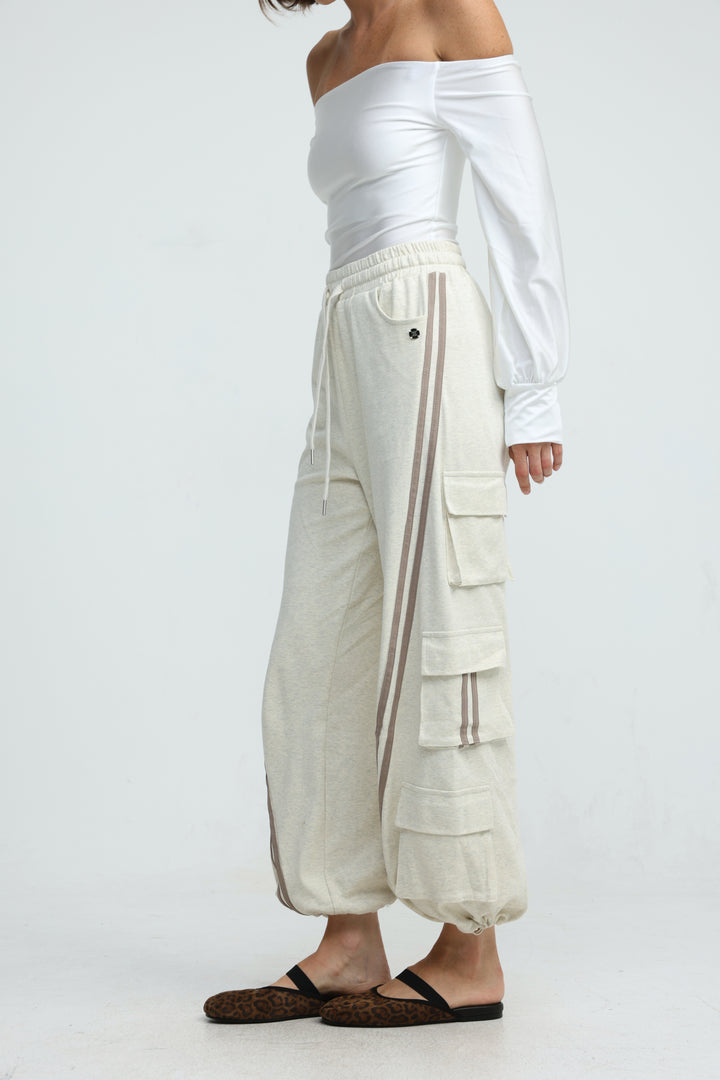 Cream-colored cargo joggers with vertical striped side panels and multiple utility pockets shown from the front