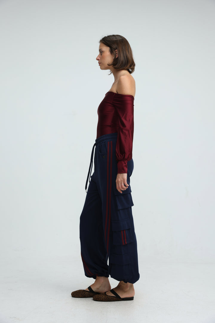 A woman wearing port navy joggers in navy blue wide-leg cargo style paired with a burgundy  off-the-shoulder top