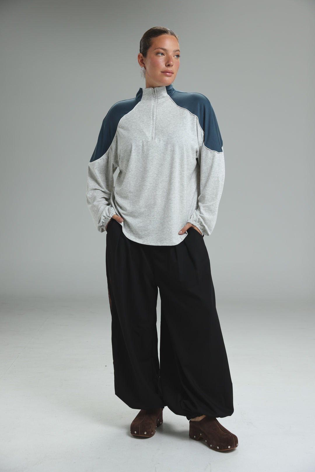 A woman wearing an allure cream sweatshirt in light gray and navy blue raglan half-zip with ribbed cuffs front view