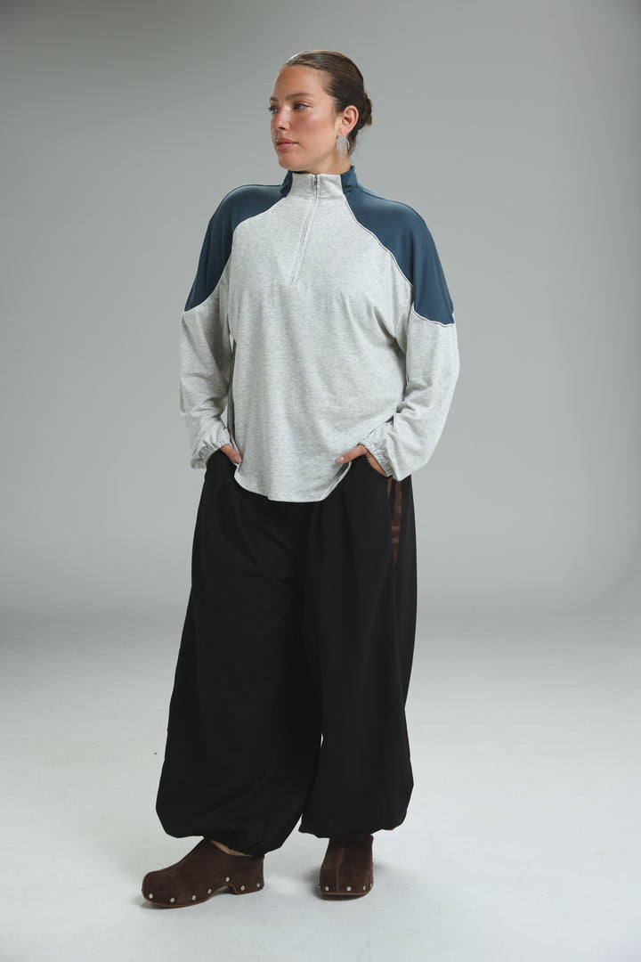A woman wearing an allure cream sweatshirt with navy blue shoulder panels and light gray body fabric front view
