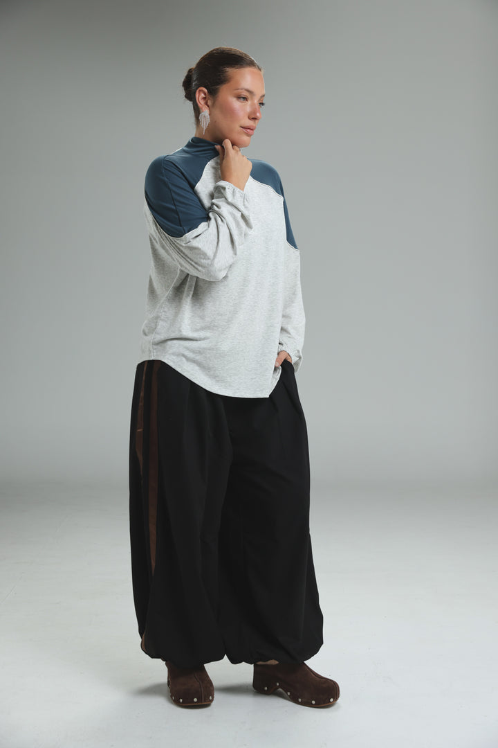 A woman wears an allure cream sweatshirt with navy blue raglan sleeves and a light gray body, shown from the front
