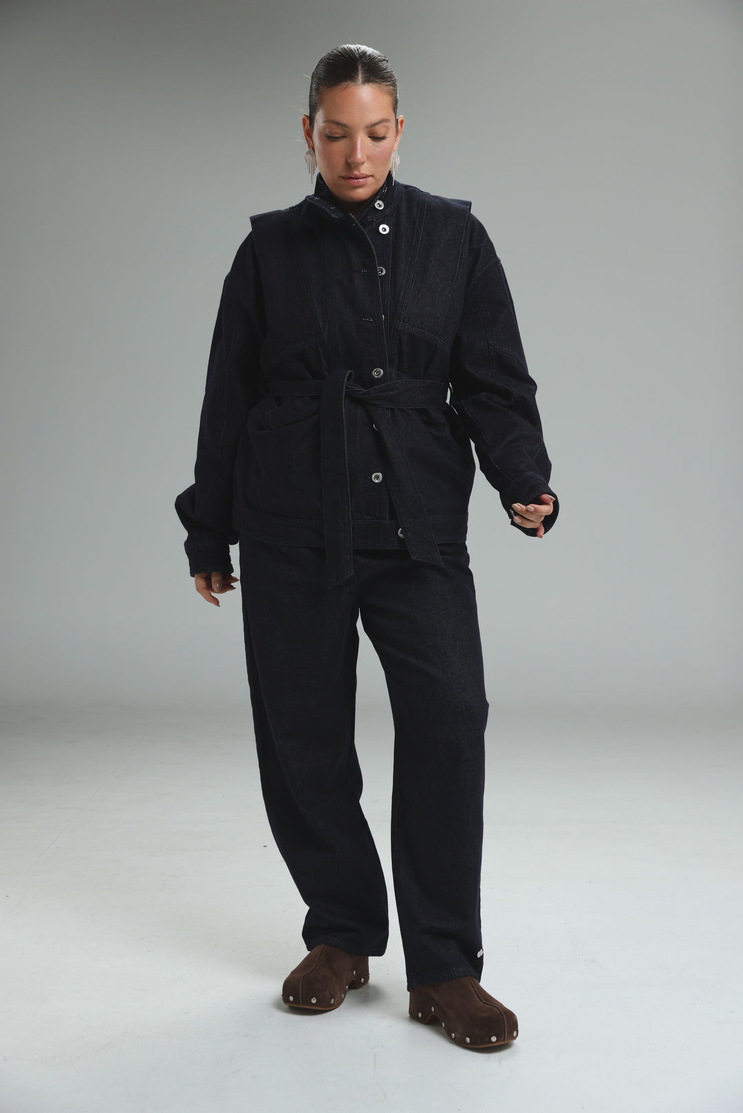 Black utility jumpsuit with button closures and belted waist shown from the front, titled prestige blue denim jacket