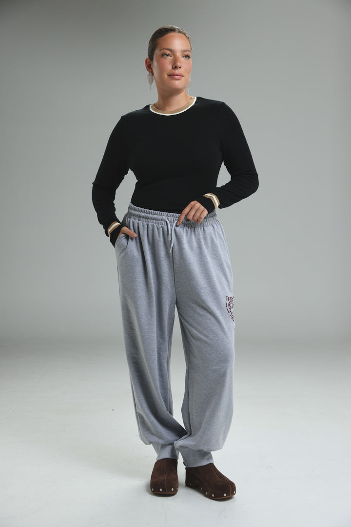 Trim black bodysuit paired with light gray loose-fitting sweatpants with drawstring waist and embroidered logo on thigh