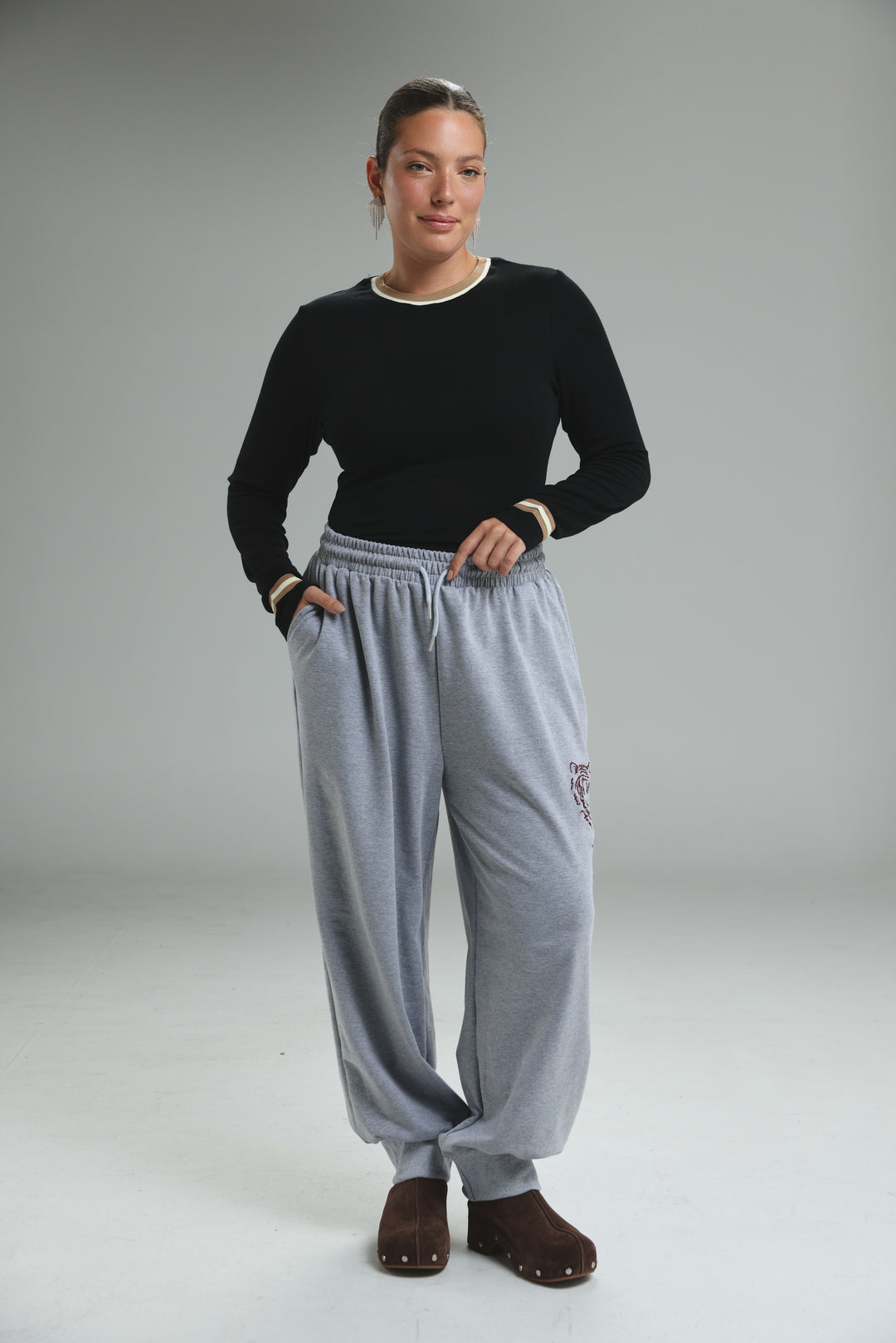 Trim black bodysuit shown with light gray sweatpants featuring drawstring waist and embroidered logo on the thigh