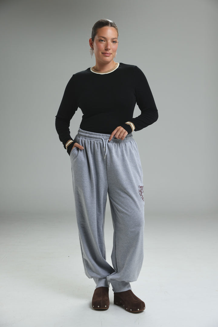 Trim black bodysuit shown with light gray sweatpants featuring drawstring waist and embroidered logo on the thigh