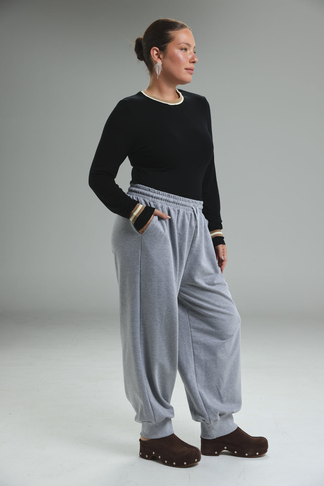 Trim black bodysuit paired with light gray joggers featuring elastic waistband and striped cuffs in front view
