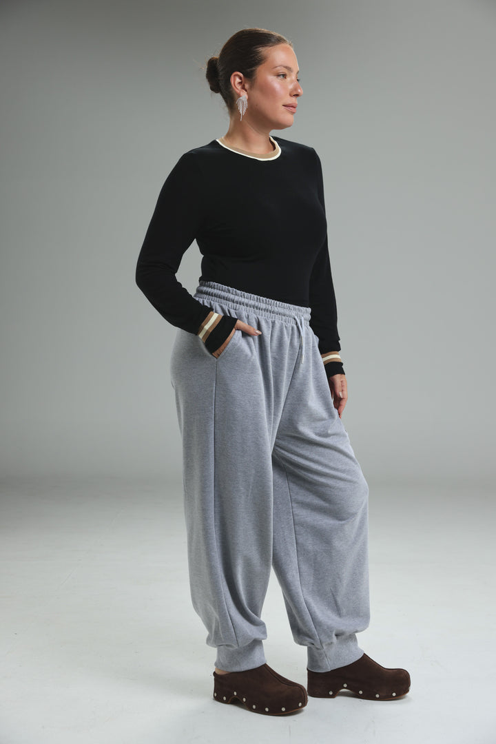 Trim black bodysuit paired with light gray joggers featuring elastic waistband and striped cuffs in front view