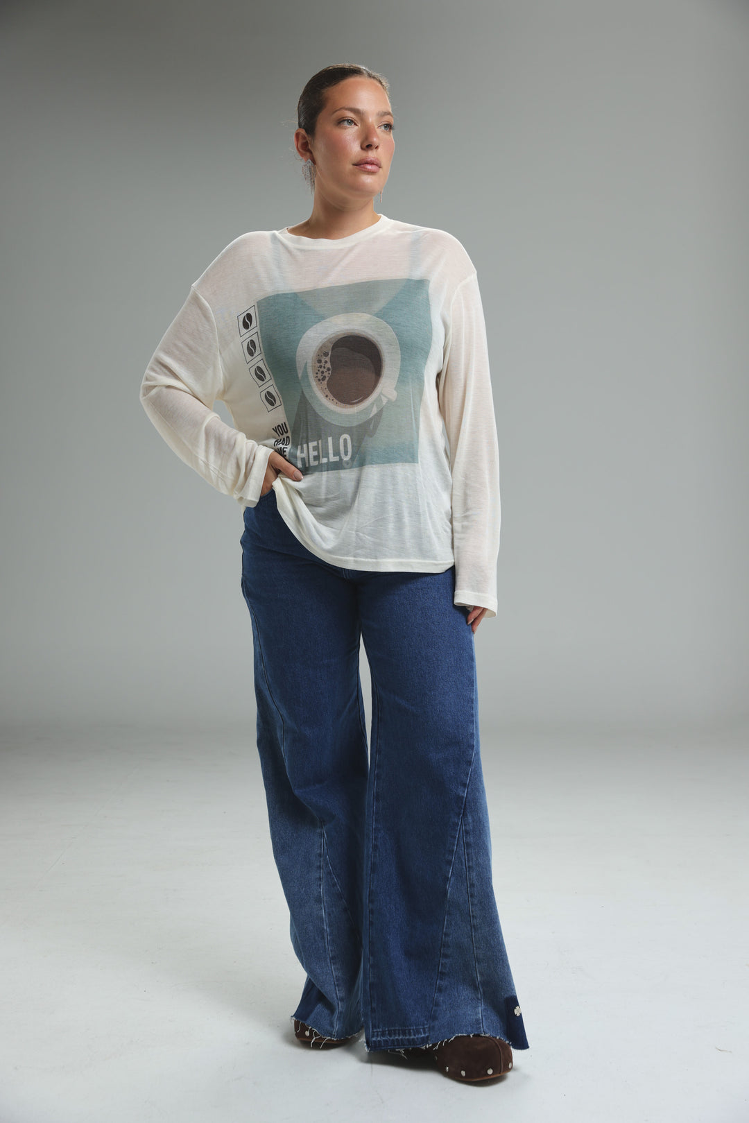 White long-sleeved graphic tee with teal coffee cup print and hello text on the front