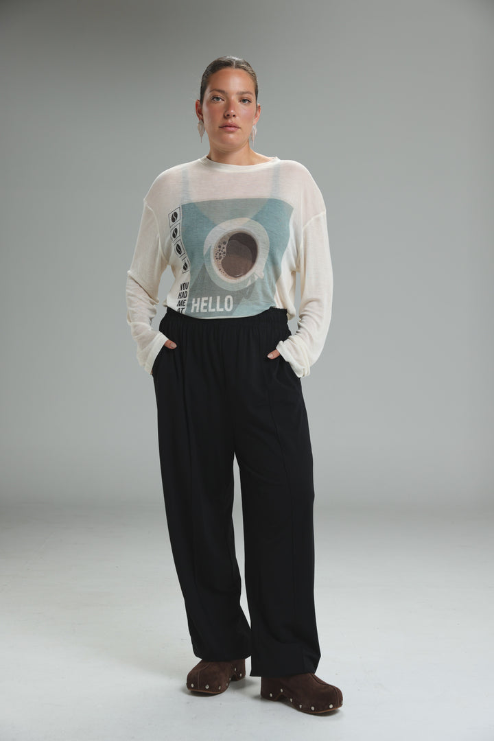 White long-sleeved top with light blue and brown hello graphic paired with best black joggers front view