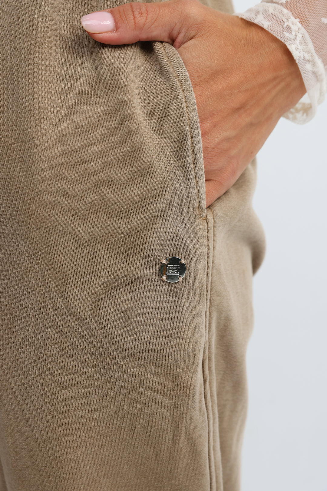 Beige textured fabric Zone camel jogger pants with a small metallic logo patch on the side seam
