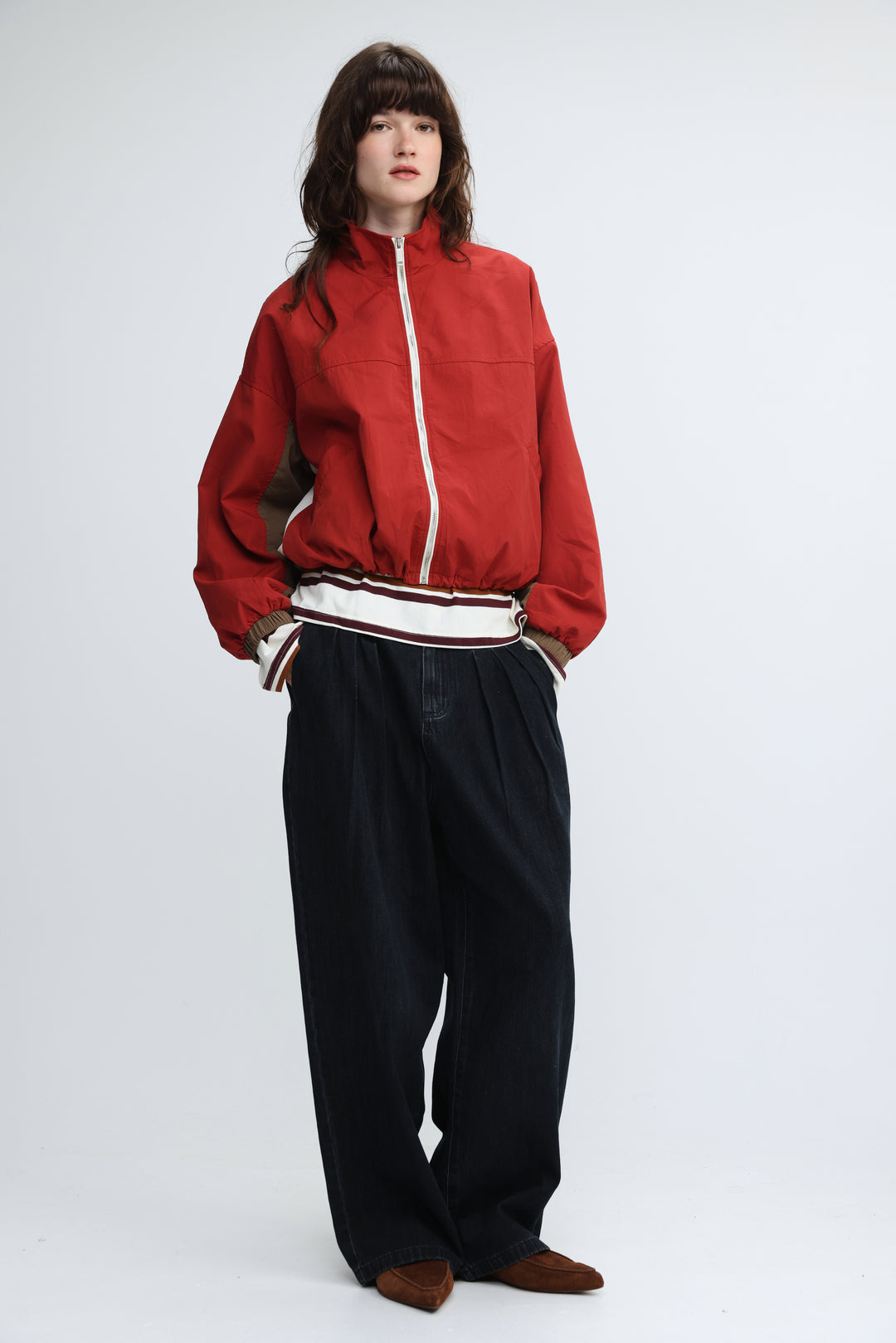 Red bomber jacket with white zipper and striped waistband shown from the front in madas red jacket product image