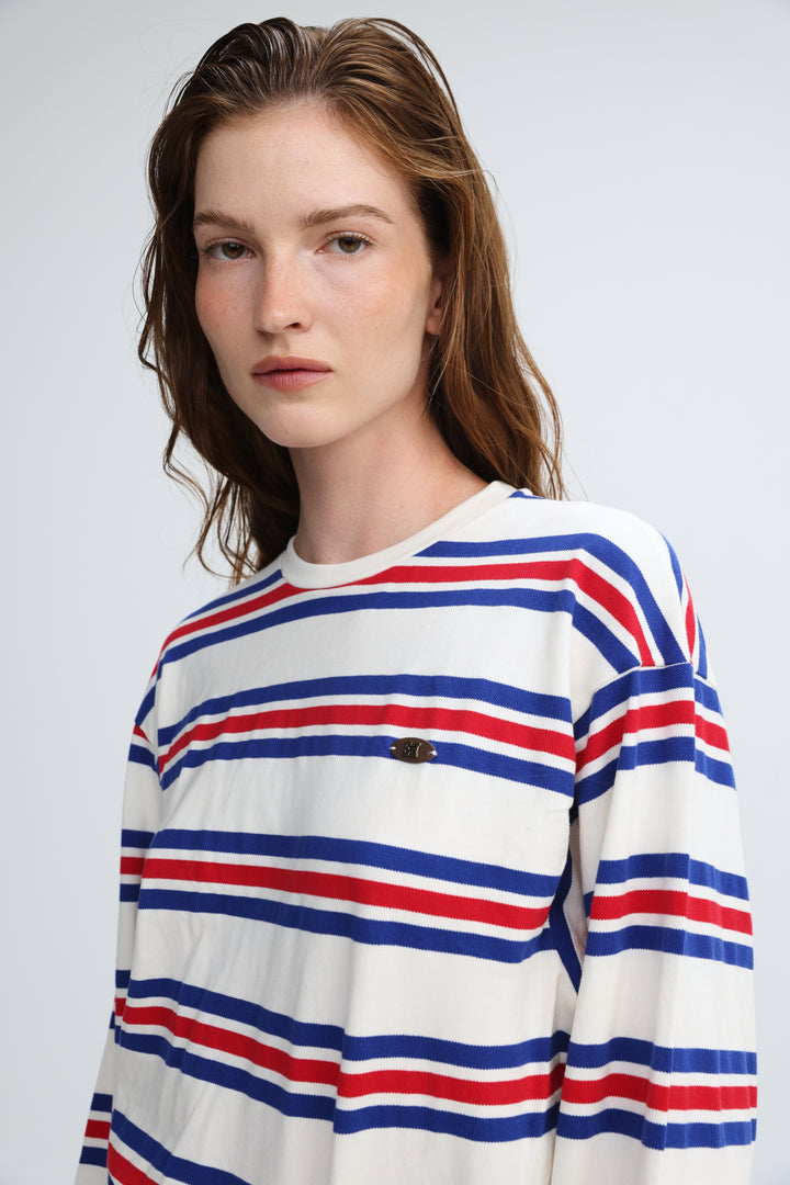 A woman wearing a long-sleeved federer blue striped shirt with horizontal red, blue, and white stripes