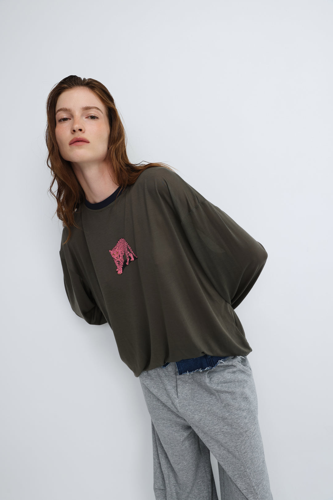 Olive green oversized long-sleeve top with a pink sequined tiger patch on the chest shown from the front