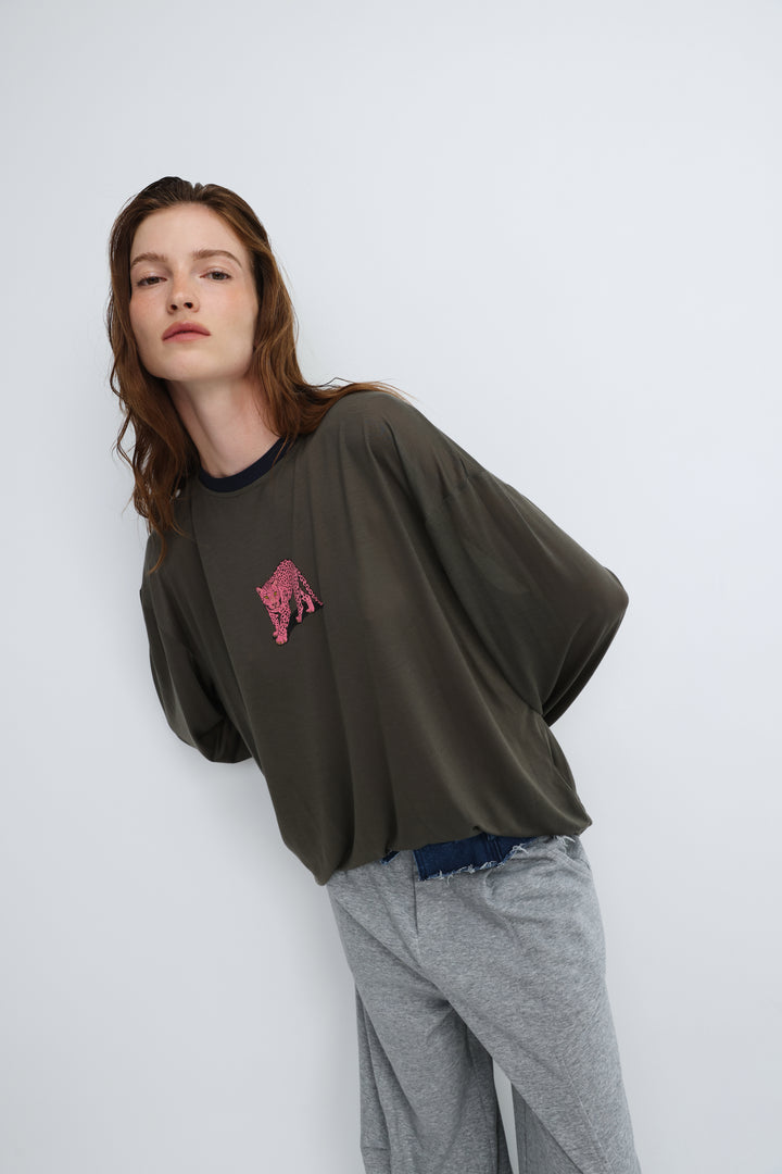 Olive green oversized long-sleeve top with a pink sequined tiger patch on the chest shown from the front
