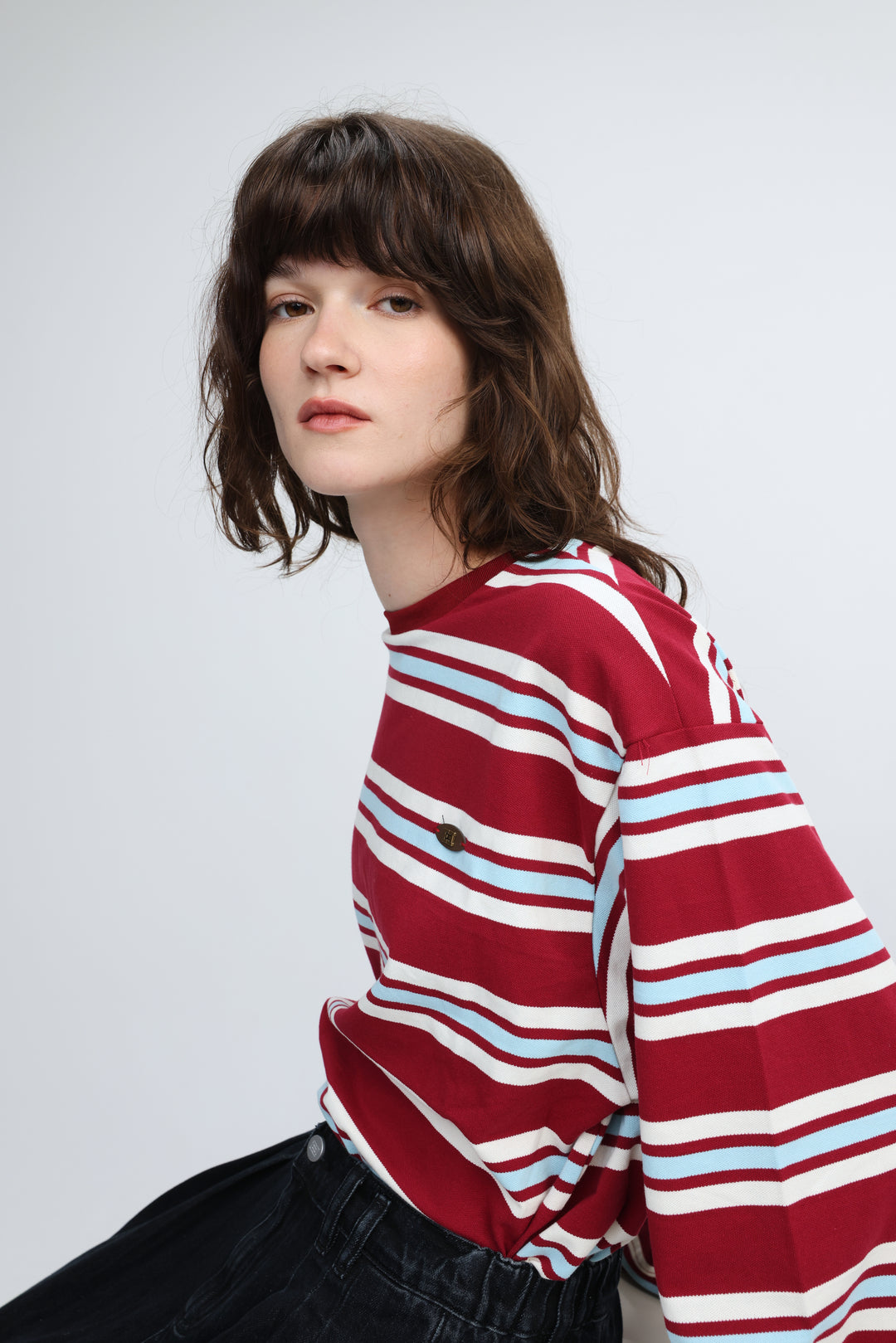 A red striped long-sleeved top with white and light blue horizontal stripes and a round neckline shown from the front