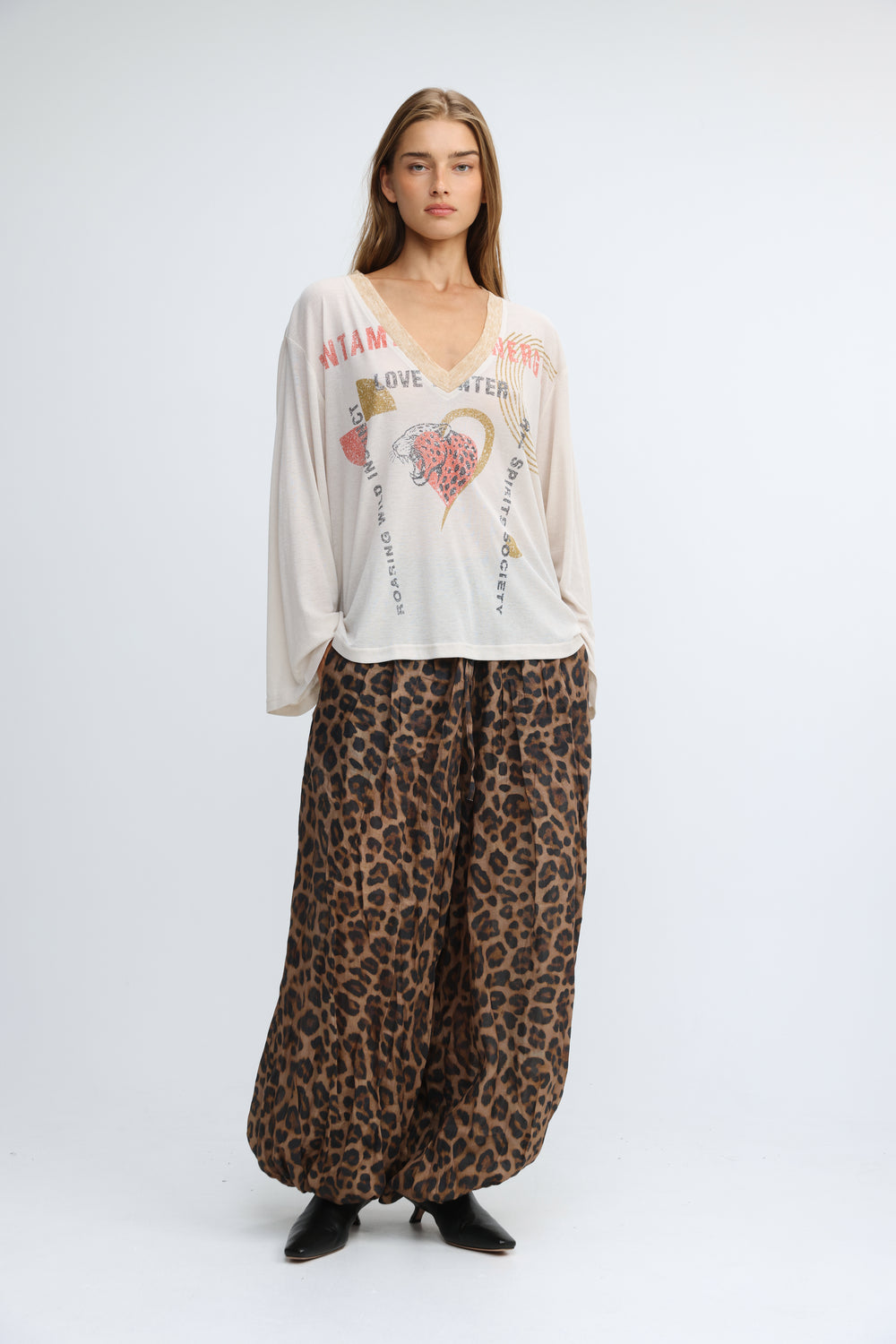 A flowing off-white long-sleeved jungle cream v shirt with a v-neck and pink and gold graphic prints on the front