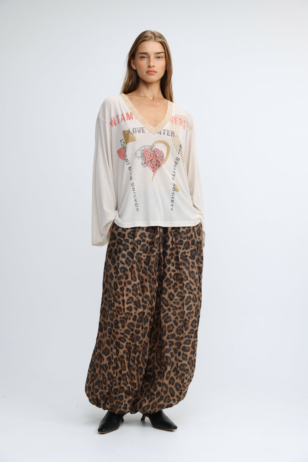 A flowing off-white long-sleeved jungle cream v shirt with a v-neck and pink and gold graphic prints on the front