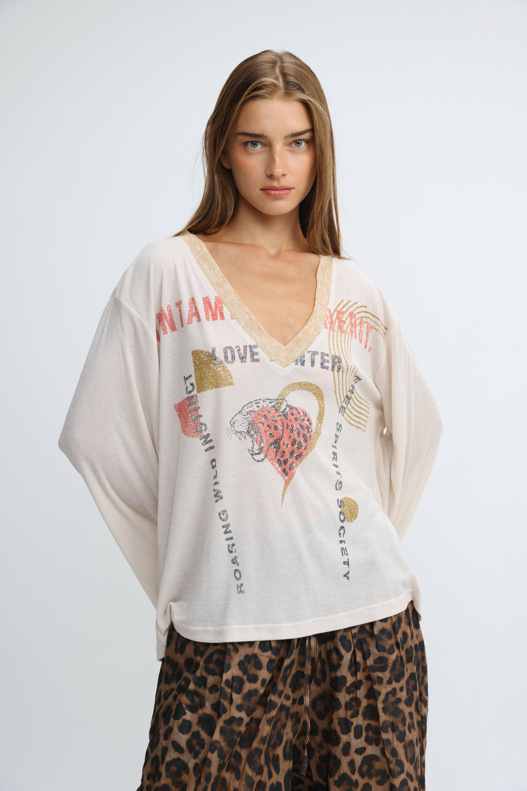 Cream-colored oversized graphic v-neck tee with bold text and a pink leopard print heart on the front