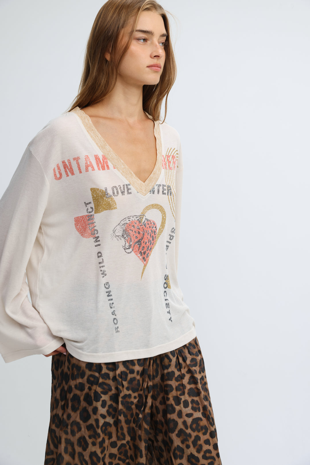 Off-white loose-fitting v-neck long-sleeved top with distressed graphic text and leopard-print heart design front view