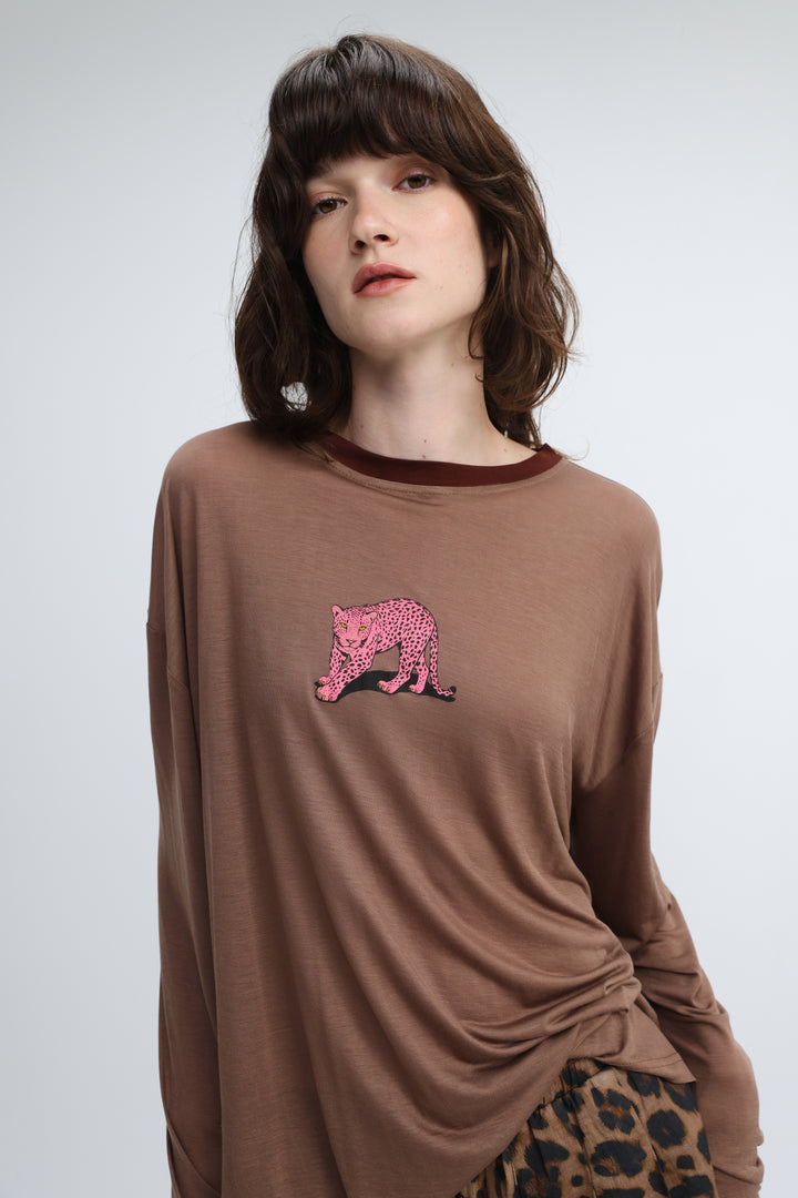 Brown long-sleeved top with pink leopard graphic on chest and dark brown ribbed neckline shown from front