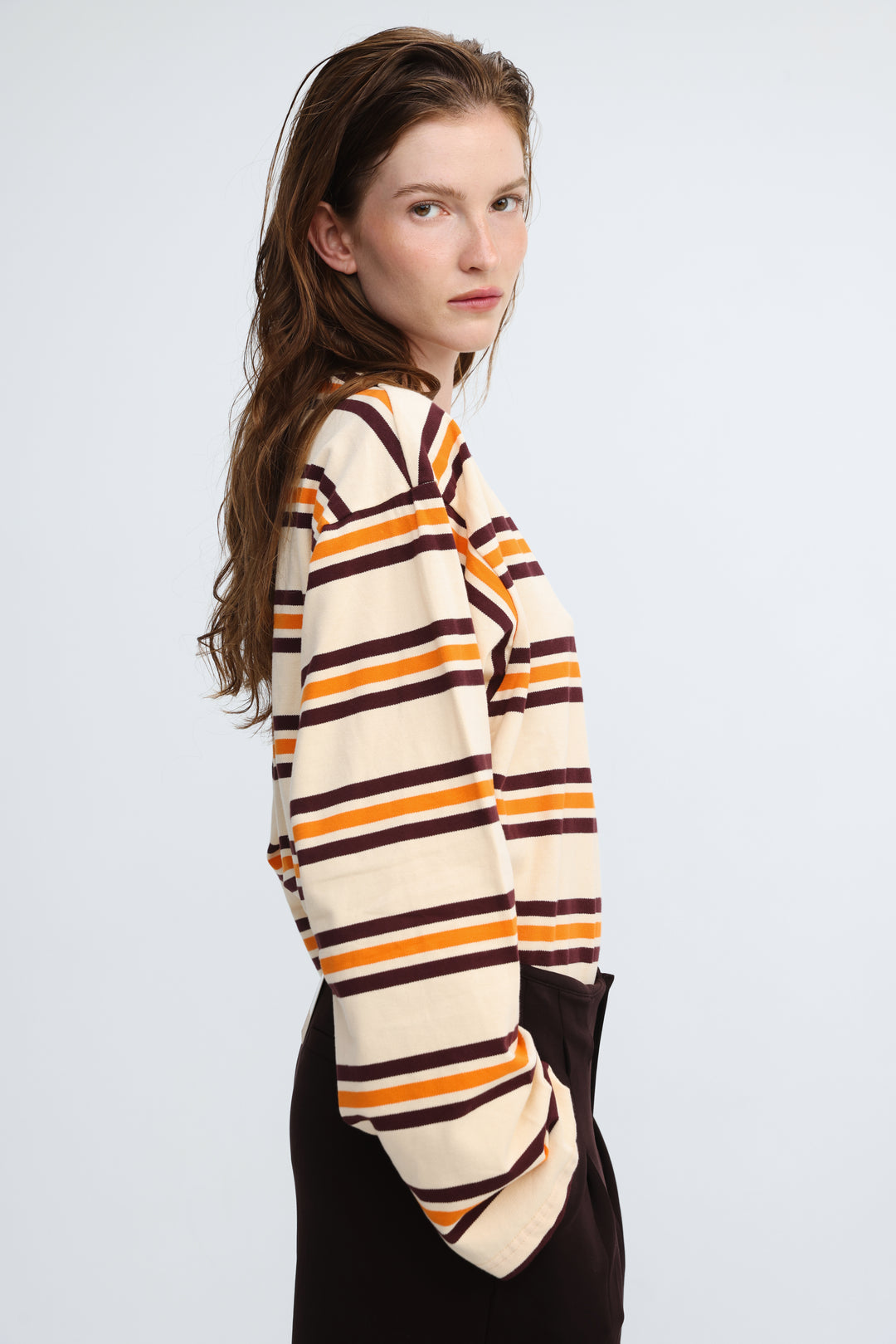 A cream orange and brown horizontally striped long-sleeved top with a relaxed fit shown from the front