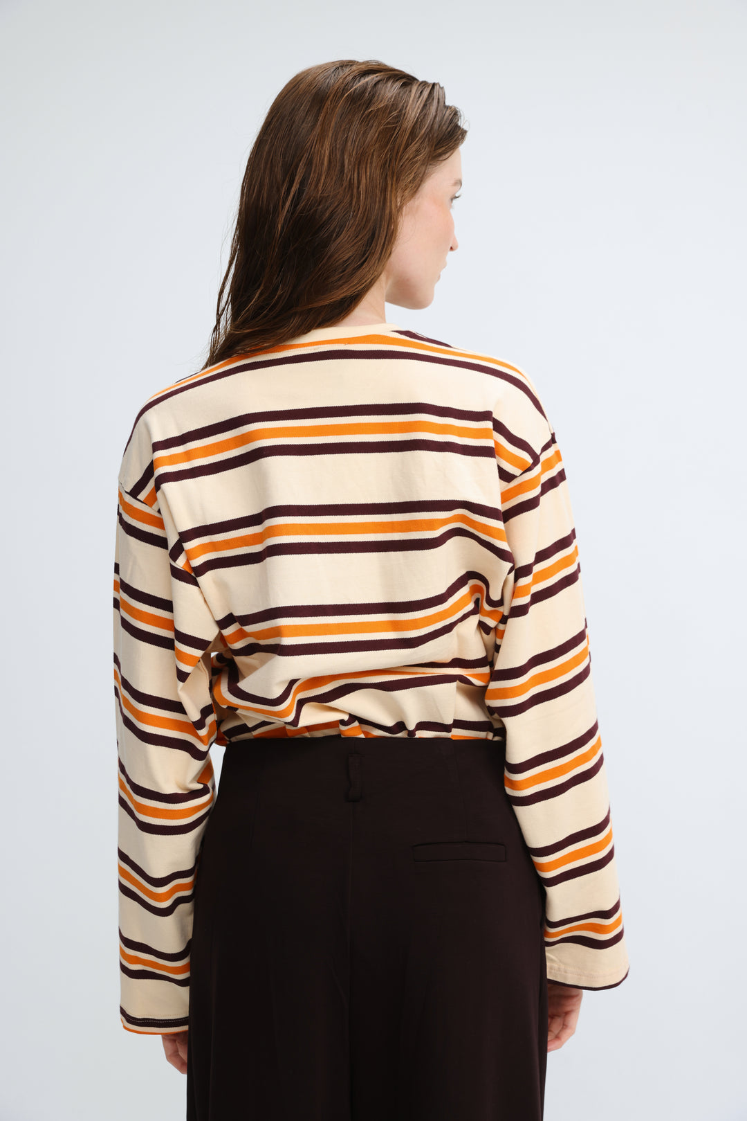 A woman wearing a front view of a long-sleeved Federer orange striped shirt with bold horizontal stripes in cream and dark brown