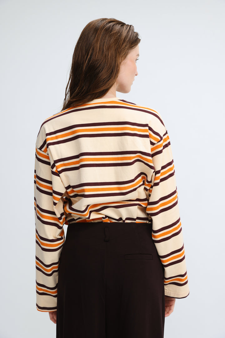 A woman wearing a front view of a long-sleeved Federer orange striped shirt with bold horizontal stripes in cream and dark brown