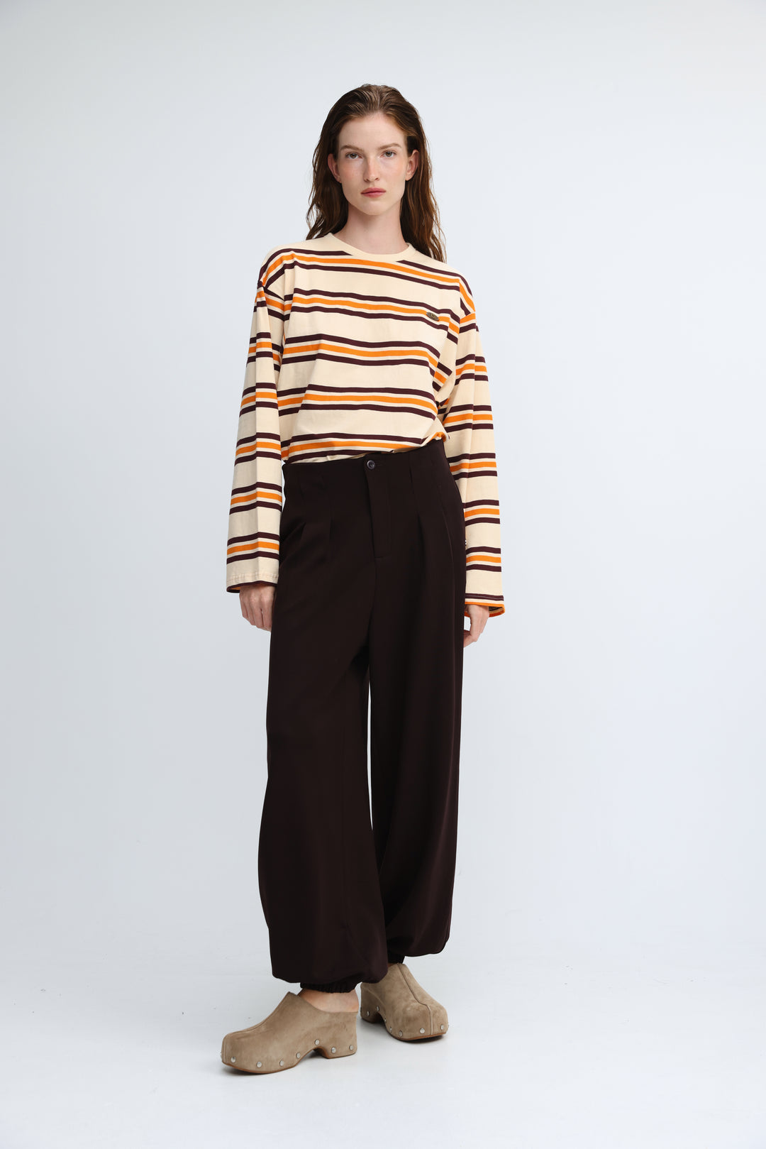 A woman wearing a front view of a long-sleeved Federer orange striped shirt with cream, orange, and black bands