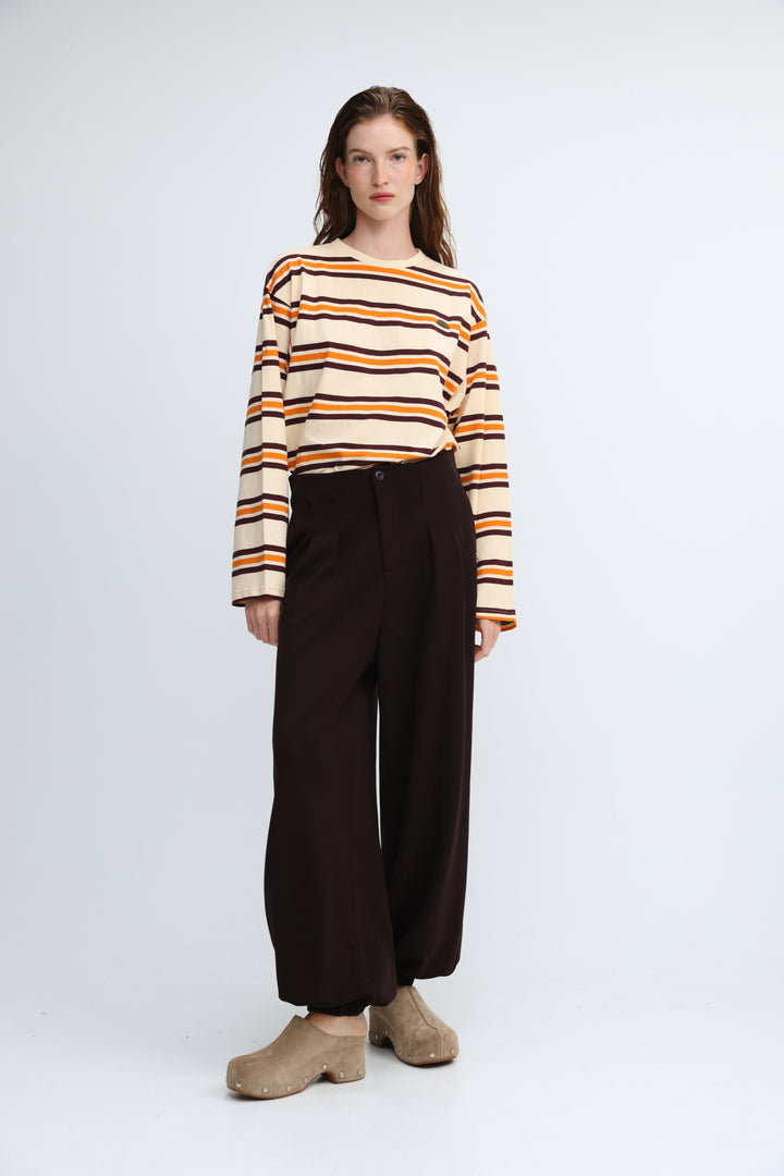 A woman wearing a front view of a long-sleeved Federer orange striped shirt with cream, orange, and black bands