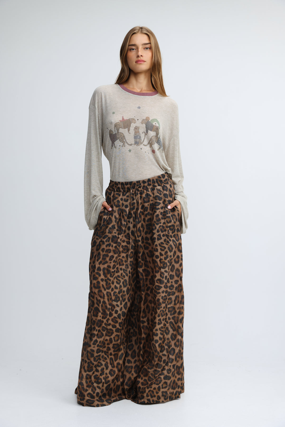 A front view of tender leopard wide bottoms paired with a long-sleeved light gray top with purple trim and animal print